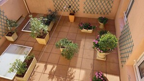 A courtyard with potted plants arranged in a grid pattern, a small wooden table, and a lattice wall. - Hotel D Angleterre (Les Sables-d'Olonne)