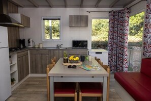 Eine kleine Küche mit Holzausbau, einem Esstisch mit Stühlen und einem roten Sofa.