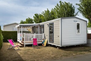 Une maison mobile dotée d’un porche couvert, d’une petite terrasse et d’une seule porte.