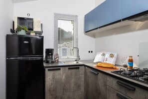 Eine moderne Küche mit einem schwarzen Kühlschrank, einer Kaffeemaschine und einem Gaskochfeld.