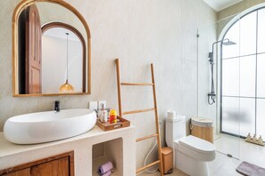 Ein modernes Badezimmer mit einem großen, ovalen Waschbecken, einer Holzleiter, einer Toilette und einer Duschkabine.
