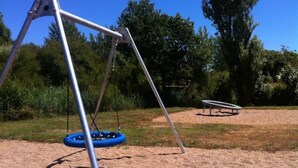 Een speeltuin met een schommel en een trampolaan.
