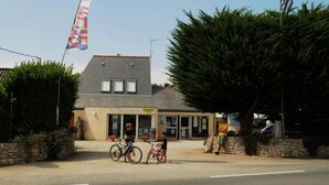 Een gebouw met een schuin dak, een kleine ingang en een bord waarop 'Le Grande Per' staat.