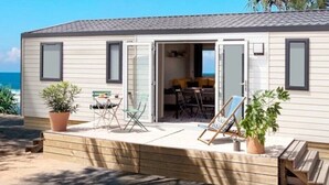 Een stacaravan met een terras, buitenmeubels en uitzicht op zee.