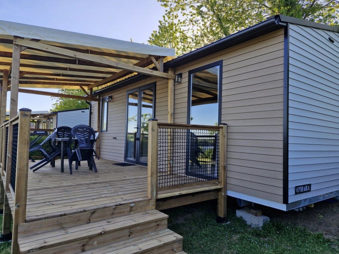 A single-story building with a covered patio area, a fenced outdoor seating area with chairs, and a nameplate on the side.