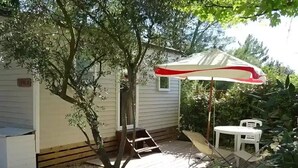 A covered patio area with a white umbrella, a small table, and a chair. - ZEcamping 3* pataugeoire piscine dog friendly mobil-home 22m2 3 pers (Junas)
