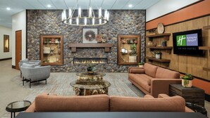 Eine Lobby mit Steinwand, Kamin, Fernseher und Sitzbereichen.