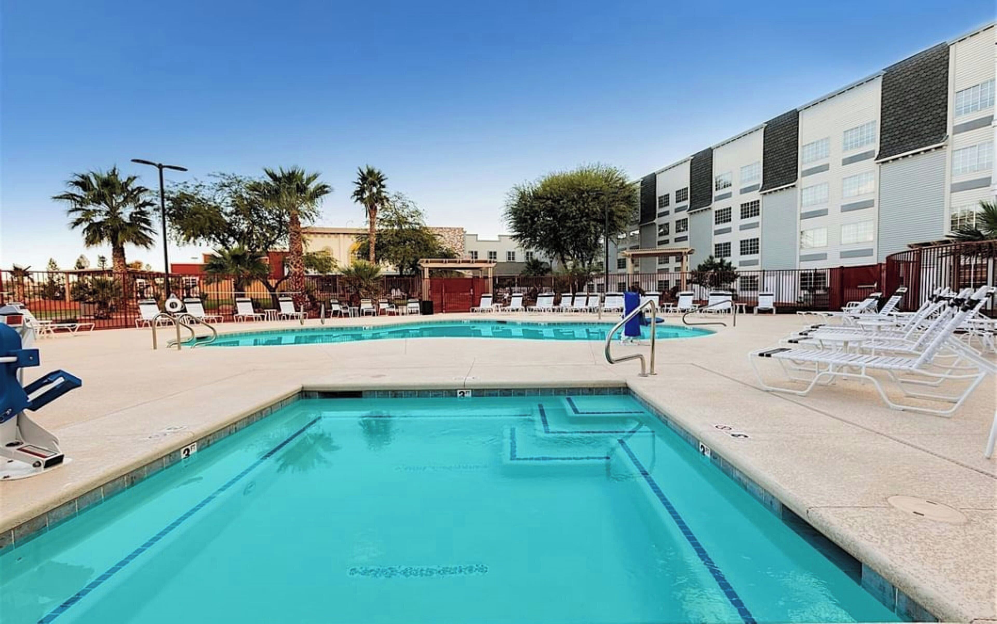 Une piscine avec des chaises longues et un bâtiment en arrière-plan.
