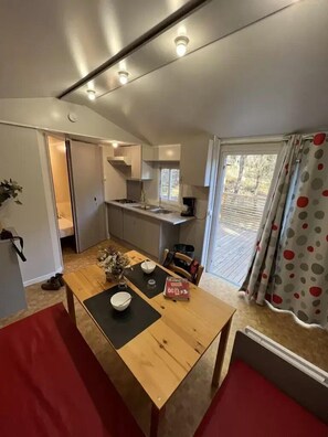 Een compacte keuken met een eethoek, een raam met gordijnen, en een kleine eettafel met stoelen.