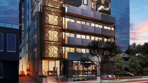 Un immeuble moderne à plusieurs étages, doté d’un mélange de balcons et de grandes fenêtres, et caractérisé par une façade originale aux motifs géométriques et une section vitrée sur le côté droit.