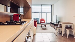 Une cuisine moderne équipée d’une cuisinière à gaz, d’une chaise rouge et d’un coin repas avec une table et des chaises.