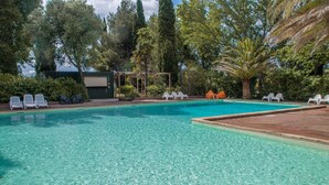 Una piscina cristalina con sillones blancos y una zona de estar techada.