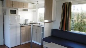 Cocina compacta con microondas, estufa y armarios, una pequeña mesa de comedor y un sofá azul.