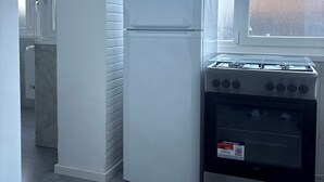 Eine Küche mit einem weißen Kühlschrank, einem Herd und einem Fenster mit Frostglas.