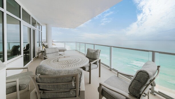 A balcony with a round table, chairs, and a view of the ocean. - Cobalt Horizon - Luxury beachfront 3 bedroom with panoramic gulf views (Destin)