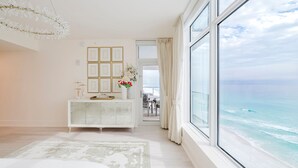 A modern bedroom with a large window, a white bed, and a view of the ocean. - Cobalt Horizon - Luxury beachfront 3 bedroom with panoramic gulf views (Destin)
