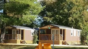 Two mobile homes with wooden decks and a playground structure in the foreground. - ZEcamping 3* piscine pet friendly mobil-home BBQ 5 pers (Sandrans)