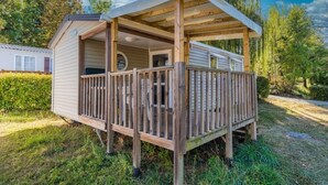 Une cabane en bois dotée d’un porche et d’une terrasse couverte.
