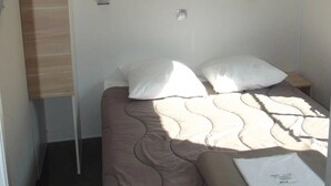 Une chambre à coucher comprenant un lit, deux tables de chevet, une étagère fixée au mur et un panneau en bois sur le mur de gauche.
