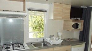 Une cuisine de taille réduite équipée d’une cuisinière à gaz, d’un évier et d’un four à micro-ondes.