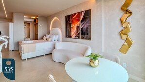 Ein modernes Hotelzimmer mit einem gewölbten Bett, einem runden Esstisch und einem großen abstrakten Gemälde an der Wand.