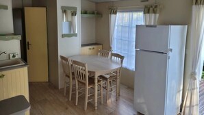 Una cocina compacta con una mesa y sillas, un refrigerador y una ventana con cortinas.