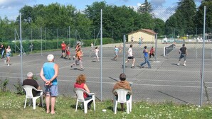 Een tennisbaan buiten met toeschouwers die op stoelen zitten.