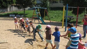 Kinderen spelen in een zandbak met speeltoestellen op de achtergrond.