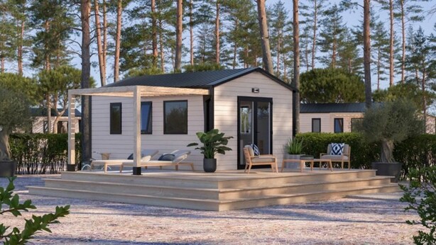 Uma cabana moderna com varanda coberta, área de estar externa e acesso por caminho de pedras.