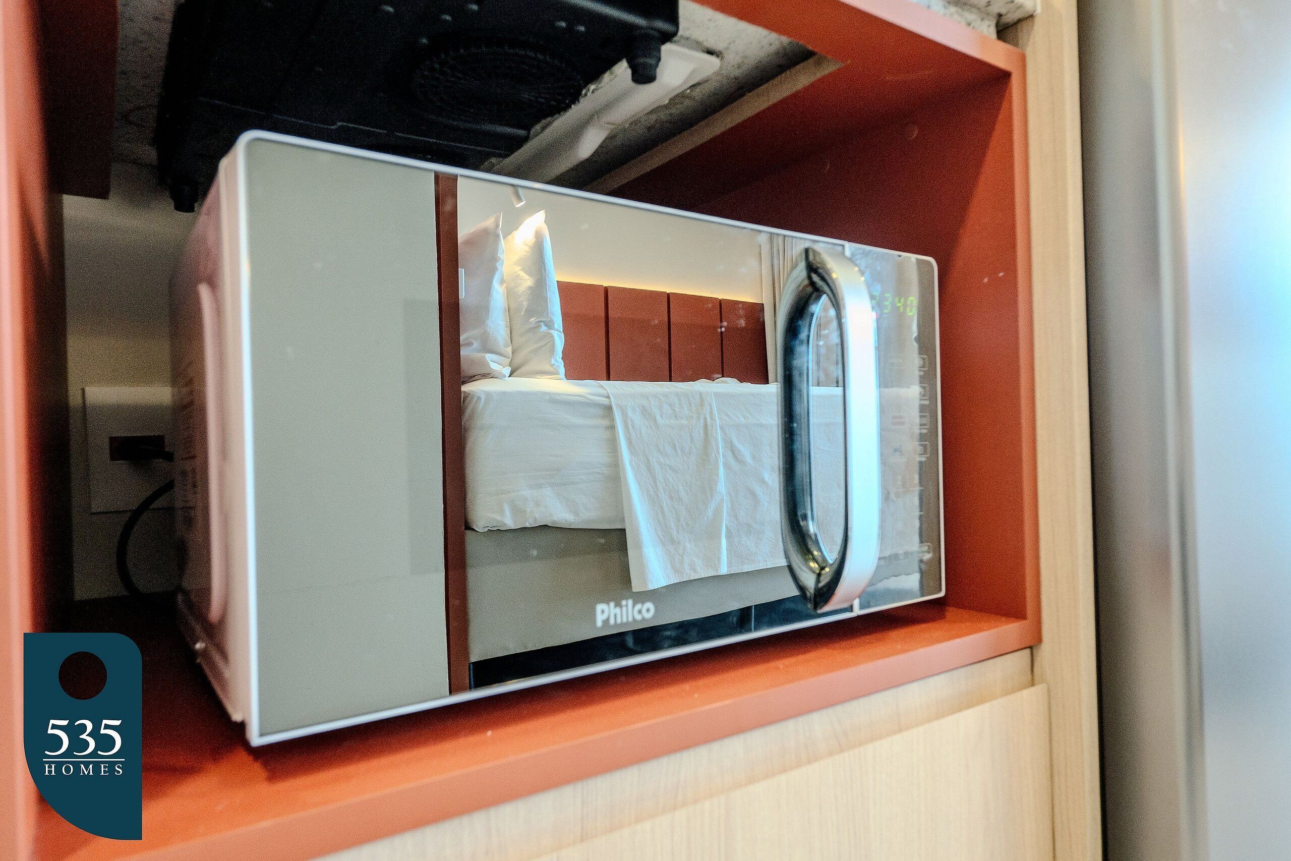 Une chambre d’hôtel de taille réduite, équipée d’un lit, d’un miroir et d’un radiateur encastré.