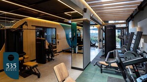 Ein modernes Fitnessstudio mit unterschiedlichen Trainingsgeräten, einer Holzwand und einem großen Spiegel.
