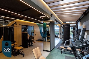 Un gimnasio moderno con diversos equipos de ejercicio, una pared de madera y un espejo grande.