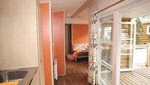 Een moderne keuken met een spoelbak en kasten, een gang die leidt naar een woonruimte met een bank en een kleine tafel, en een schuifdeur naar een terras.