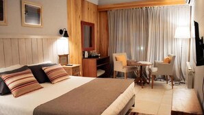 A hotel room with a large bed, a desk, a chair, and a small table. - Las Bayas Home Suites (Esquel)