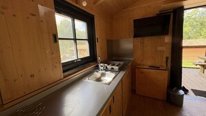Un interior de madera con una cocina, que incluye un lavabo, estufa y un televisor montado en la pared.