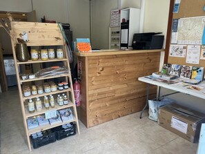 A wooden counter with jars of honey and honeycomb, a fire extinguisher, and a bulletin board with various notices. - Camping 3 étoiles - Piscine  - ccbfa0h (Saint-Mandé-sur-Brédoire)