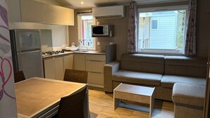 Un espacio habitable compacto con kitchenette, zona de comedor y sala de estar con sofá y mesa de centro.