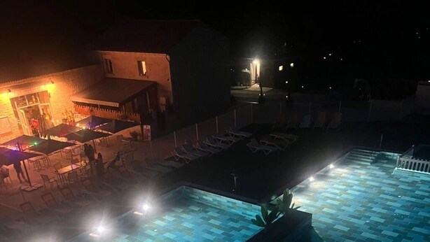 Un área de piscina en la azotea, con piso de baldosas y algunas sillas de descanso.