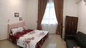 A bedroom with a bed, a wooden wardrobe, a small table, and a sofa.