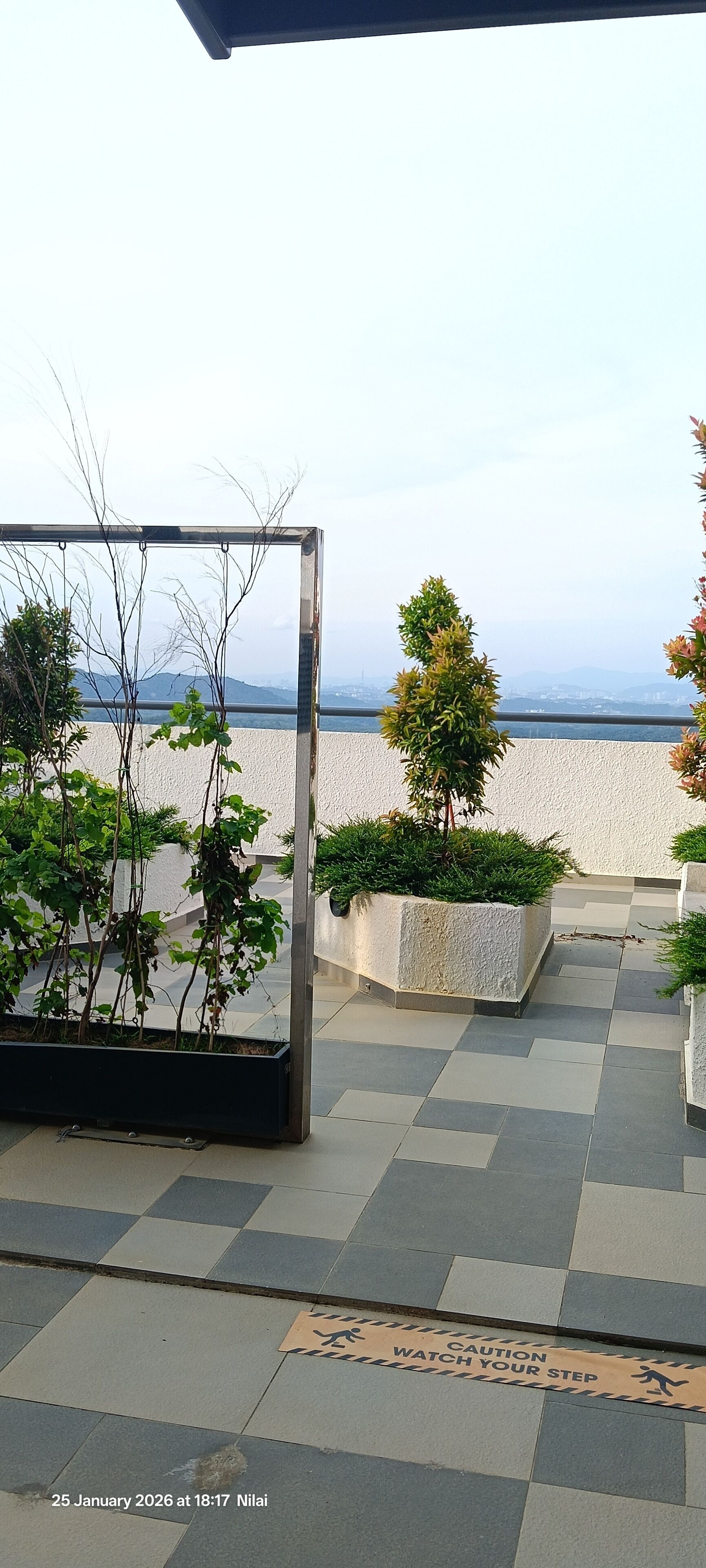 A terrace with potted plants, a metal frame structure, and a view of the sea.