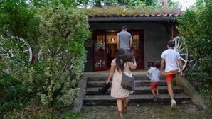 Eine Familie steigt eine Steintreppe zu einem Gebäude mit einem Ziegeldach hinauf.