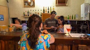 Eine Bar mit einer Theke, alkoholischen Getränken in Regalen und einer Person, die Getränke ausschenkt.