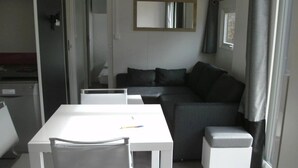 Uma sala de estar moderna com um sofá cinzento, uma mesa branca e uma cadeira.