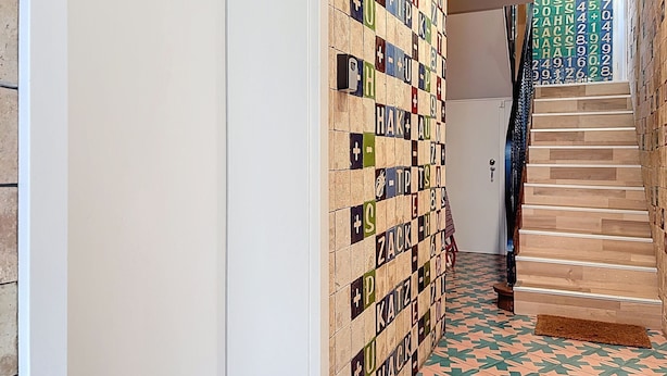 Un pasillo con un revestimiento mural estampado y una escalera con piso de diseño.
