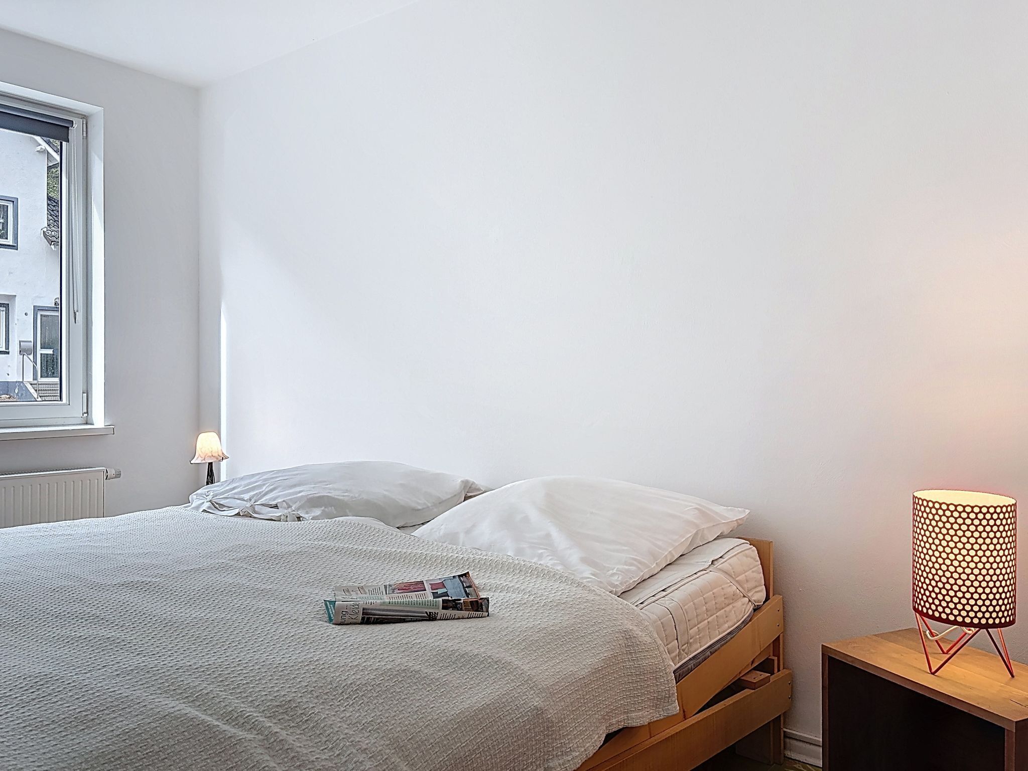 A bedroom with a bed, a bedside lamp, and a window.