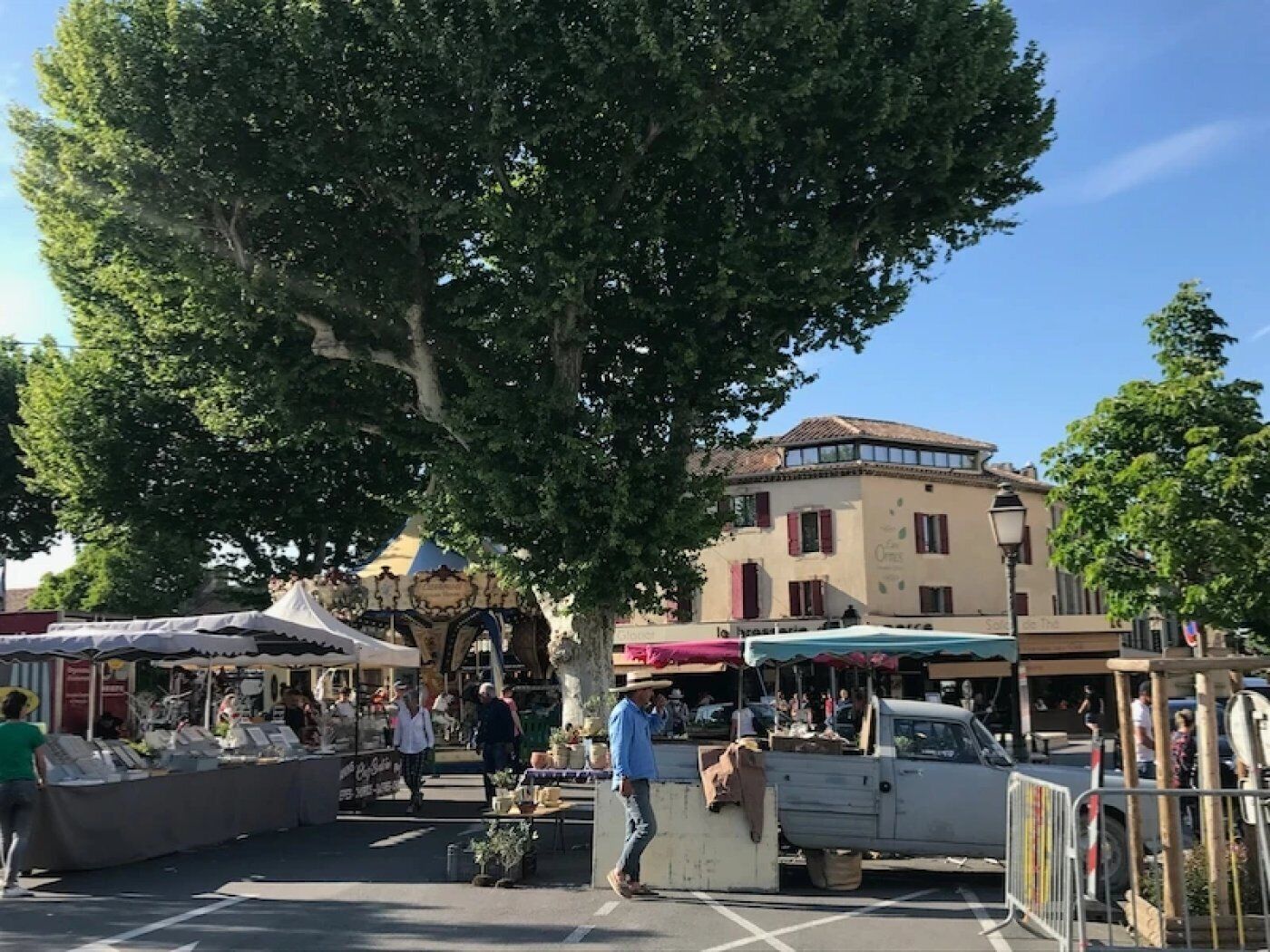 A street market with stalls and a white truck parked on the side.