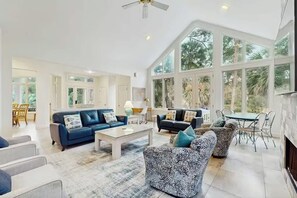 A spacious living room with a high ceiling, large windows, and a fireplace. - Lagoon Path to Beach | Pool & Golf (Hilton Head Island)