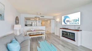 Een moderne woonkamer met een bank, een eettafel en een televisie waarop het logo van 'Big Fish Rentals' staat.