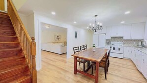 A spacious kitchen with white cabinets, a wooden dining table, and a staircase. - Private Villa for Family and group getaway + pool (Murrells Inlet)