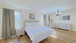 A bedroom with a bed, a nightstand, a dresser, and a chair. - Private Villa for Family and group getaway + pool (Murrells Inlet)